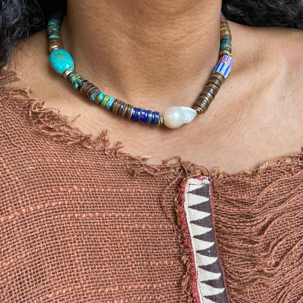Collier puka ras de cou en Coquillage, Turquoise, Lapis Lazuli, Perle d'eau douce baroque et Perles de verre anciennes, et laiton doré plaqué or 24 carats.  Longueur réglable de 40cm à 45cm.  La version précieuse du collier de surfer.  Les pierres étant naturelles et uniques, de légères différences de couleurs et de formes peuvent changer l'apparence du bijou.
